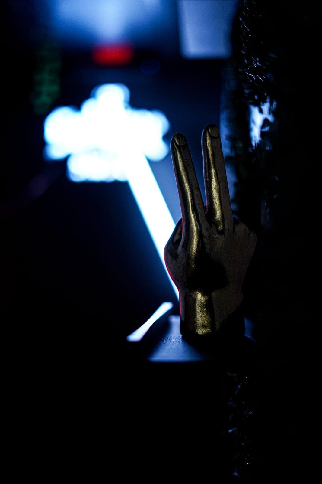 Gold hand sculpture under a neon sign