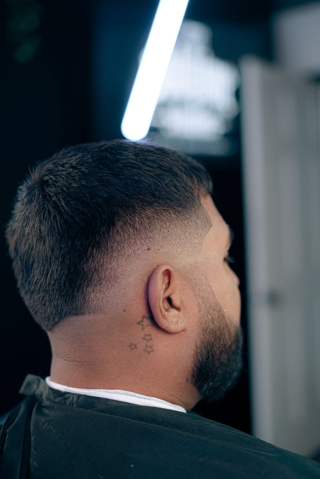 Skin fade from behind, neck tattoo showing